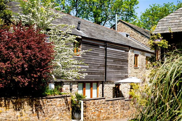 Exterior of Corn Barn showing stone and slate and surrounding shrubs